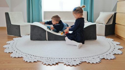 Lille dreng bruger chaiselongen i skumklodser som rutjsebane hvor en bil kører op